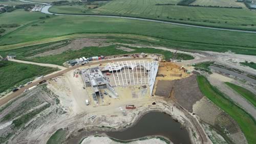 Billede 1: Dronefoto (fra Stauning Maskinstation A/S) af opførelsen af Naturkraft samt jordopfyldningen mod bygningen.